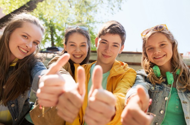 teenage friends or students showing thumbs up